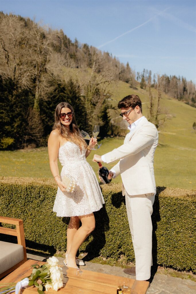 cute couple celebrating their engagement in switzerland with champagne
