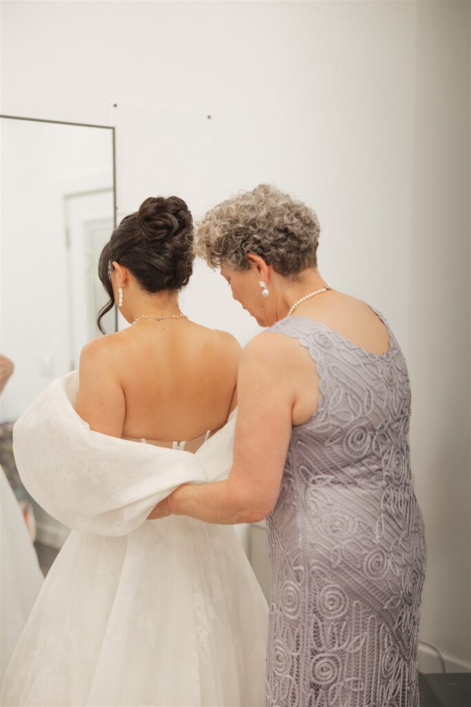 mother of the bride helping her with the wedding dress