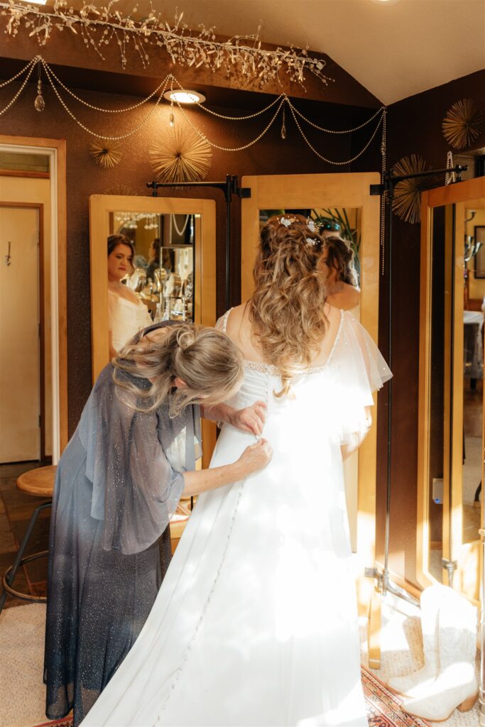 mother of the bride helping her with her wedding dress