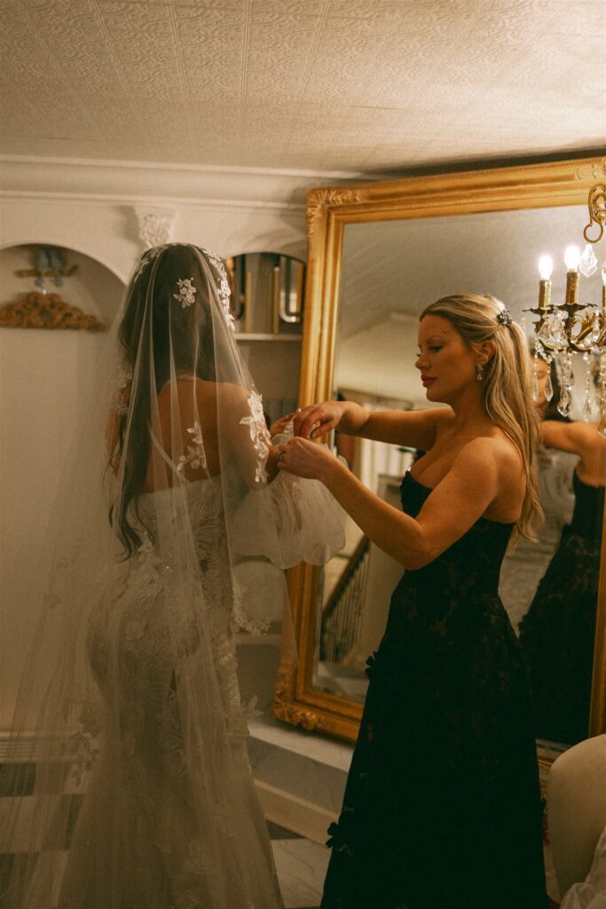 sister of the bride helping her with the wedding dress