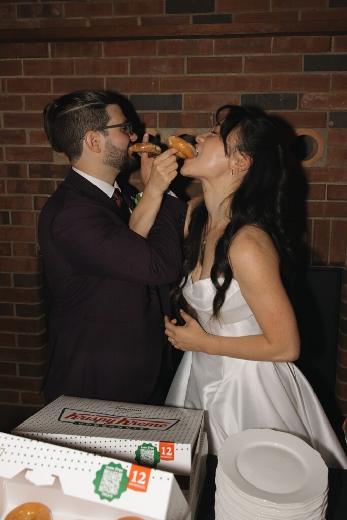newlyweds having donuts at their wedding reception