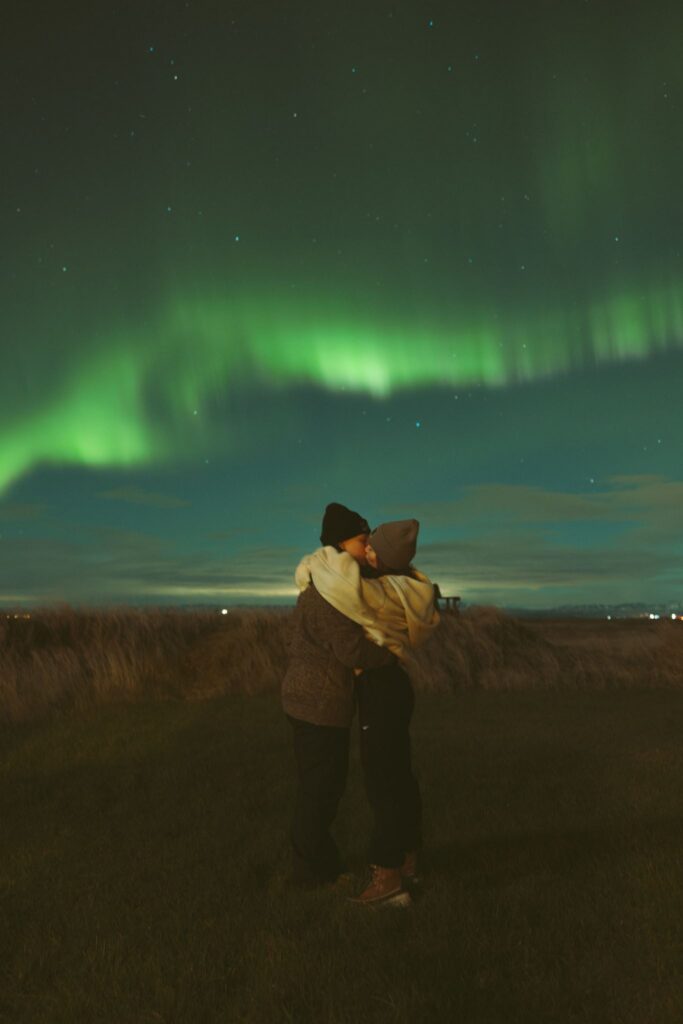 happy couple seeing the northern lights in iceland
