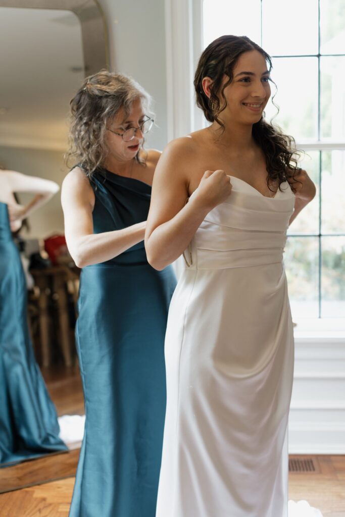 mother of the bride helping her with the wedding dress