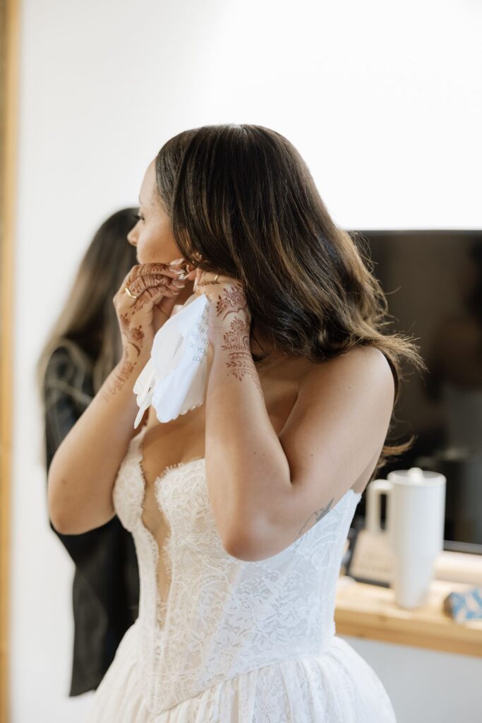bride putting on her jewelry before the ceremony