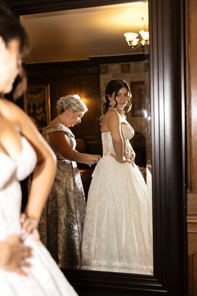 Mother of the bride helping her with the wedding dress