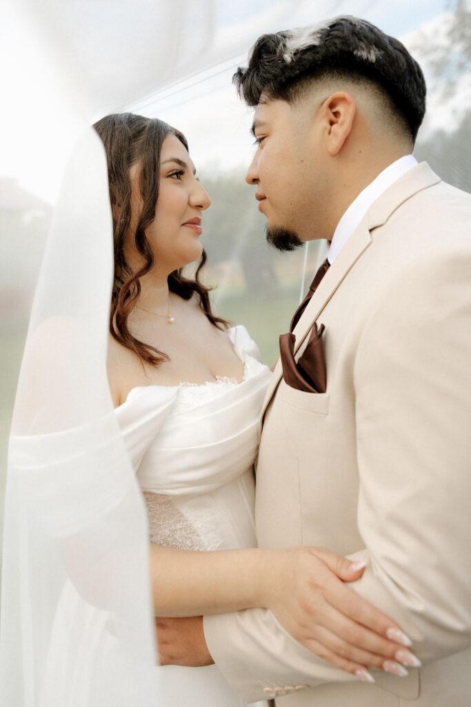 bride and groom smiling at each other during their romantic bridal portraits
